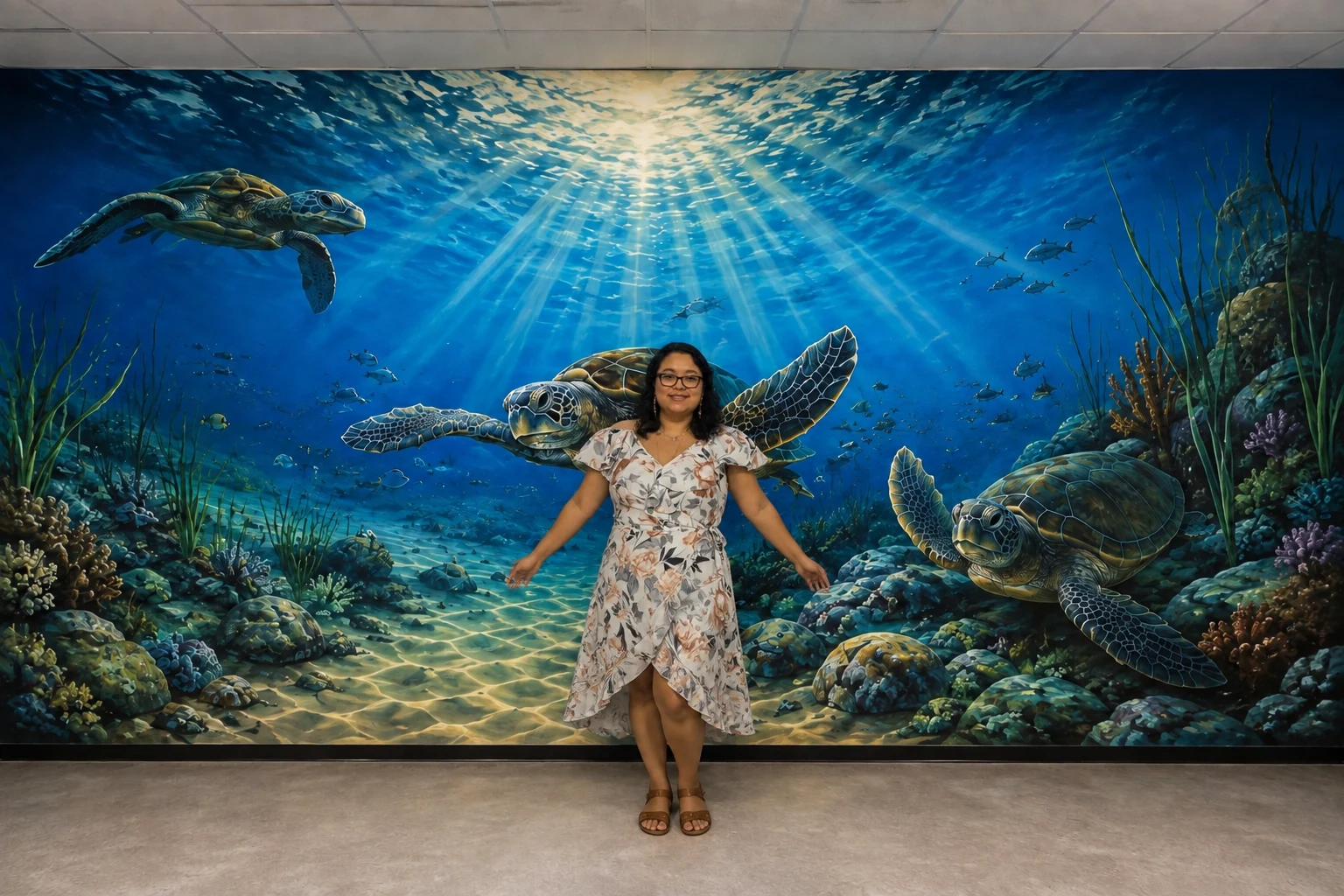 Guest standing in front of a large sea turtle underwater mural